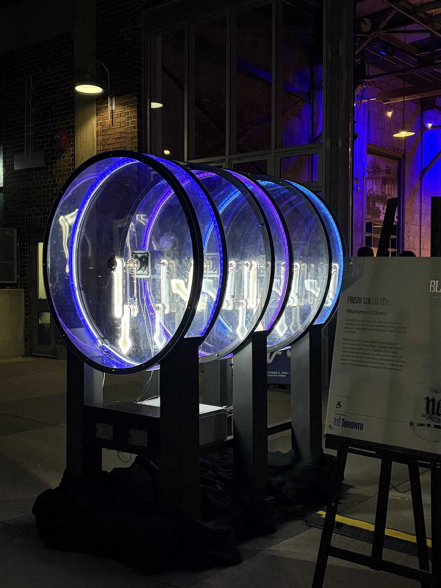 Portrait view down the row of illuminated double pendulums at the exhibition